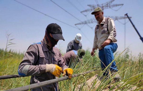 فنيون من كوادر وزارة الكهرباء العراقية يصلحون أحد أبراج نقل الطاقة المتضررة يوم 4 آب/أغسطس. ويشتبه بتنفيذ تنظيم داعش سلسلة من الهجمات على أبراج الطاقة خلال الشهر الماضي. [وزارة الكهرباء العراقية]