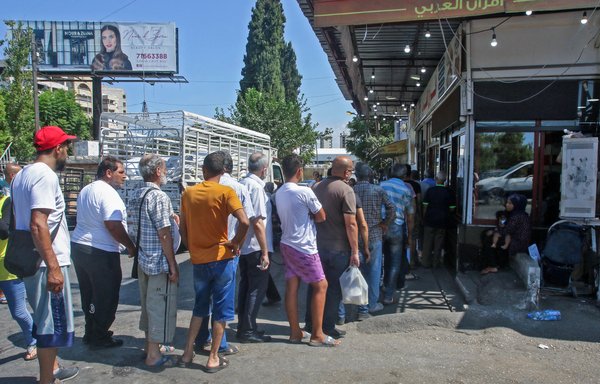 Lebanese queue for bread in front of a bakery in the southern coastal city of Sidon on August 13 amidst a deepening economic crisis sparking various shortages of basic staples in the country. [Mahmoud Zayyat/AFP]