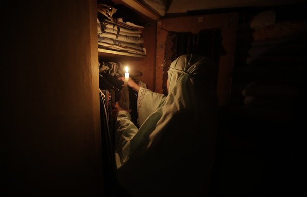 سيدة لبنانية تستخدم ضوء شمعة لترتيب الملابس في بيروت بتاريخ 10 تموز/يوليو وسط انقطاع حاد للكهرباء في البلد الذي تعصف به الأزمات. [أنور عمرو/وكالة الصحافة الفرنسية]