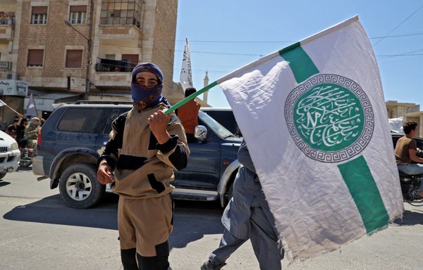 A Tahrir al-Sham element holds the flag of the extremist alliance in Idlib, Syria, on August 20. [Omar Haj Kadour/AFP]