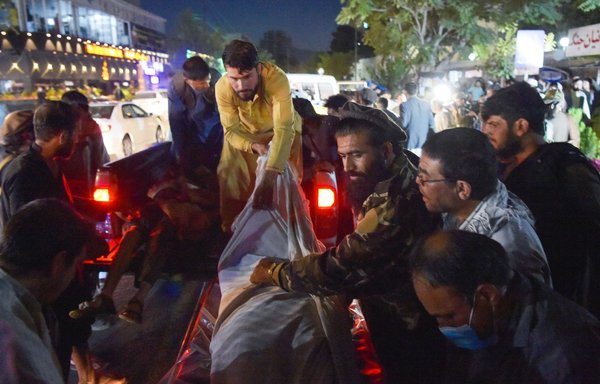 Volunteers and medical staff unload bodies from a pickup truck outside a hospital after two powerful explosions detonated outside the airport in Kabul on August 26. [Wakil Kohsar/AFP]