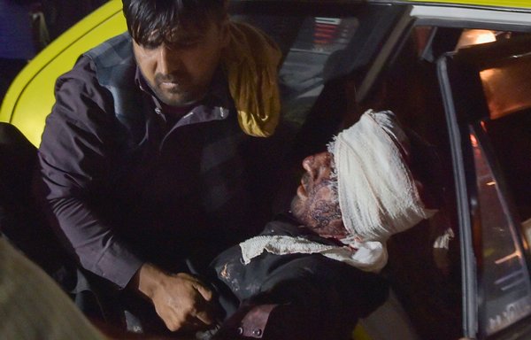 Medical and hospital staff carry an injured man out of a car for treatment after two blasts went off outside the airport in Kabul on August 26. [Wakil Kohsar/AFP]