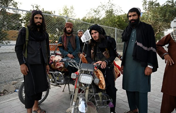 Taliban fighters stand along a road in Kabul on August 18. [Wakil Kohsar/AFP]