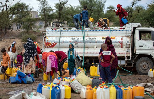 Yemeni women and children fill their jerricans with water from a tanker in al-Maafer district on August 26 amid extreme heat and severe water shortages. [Ahmad al-Basha/AFP]