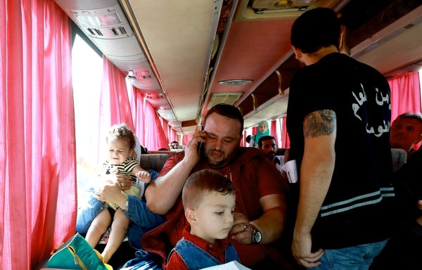 Syrian refugee Rawad Kurdi, 30, sits with his wife and children inside a bus on September 17, 2018, as they return to Syria after living as refugees in Lebanon for years. [Anwar Amro/AFP]