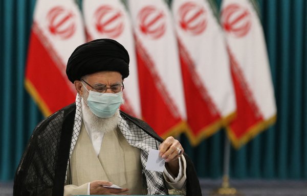 علی خامنه‌ای، رهبر ایران در ٢٨ خردادماه درحالی‌که ماسک محافظ زده است رأی خود را برای انتخابات ریاست جمهوری در یک مرکز رأی‌گیری در تهران به صندوق می‌اندازد. خامنه‌ای که به دلیل نحوه مواجهه با همه‌گیری ویروس کرونا مورد انتقاد قرار گرفته است، در ابتدا واردات برخی از واکسن‌های کرونا را ممنوع کرد، اما اخیراً حرف‌هایش را پس گرفت. [عطا کناره/خبرگزاری فرانسه]