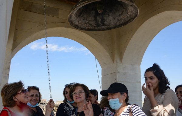 People ring the newly inaugurated bell at the Syriac Christian church of Mar Tuma in Mosul on September 18, seven years after ISIS overran the city and proclaimed Mosul its 'capital', before it was driven out three years later by the Iraqi army. [Zaid al-Obeidi/AFP]