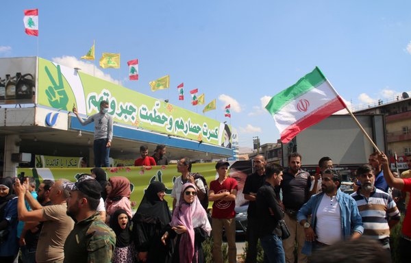 People raise an Iranian flag as they gather to welcome tankers carrying Iranian fuel upon their arrival from Syria in Baalbek in Lebanon's Bekaa Valley on September 16. [AFP]