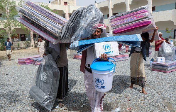 Displaced Yemenis receive humanitarian aid provided by the United Nations High Commissioner for Refugees and Rawabi al-Nahda Organisation in the Abs region of Hajjah province on August 1. [Essa Ahmed/AFP]
