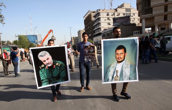 Iraqis hold portraits of the Houthi leader in Yemen, Abdulmalik al-Houthi (R), and of former IRGC Quds Force commander Qassem Soleimani during a demonstration in Baghdad's Firdous Square in 2015. [Ali al-Saadi/AFP]