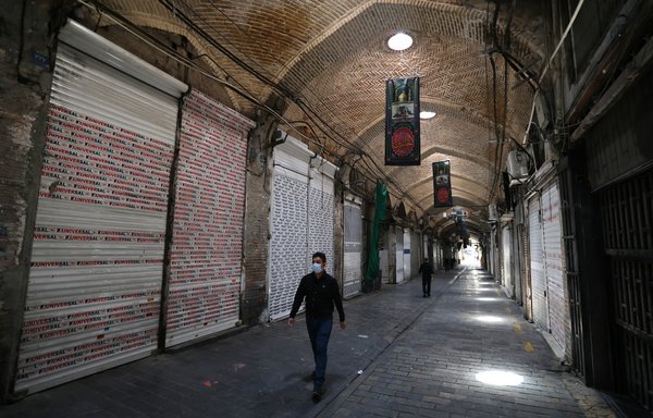 Iranians walk past shuttered stores at the Tehran Bazaar in downtown Tehran, on August 16, at the start of renewed restrictions for five days to mitigate the spread of the covid pandemic. [Atta Kenare/AFP]