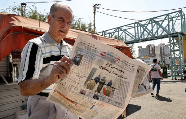 An Iranian man reads a copy of the daily newspaper Etalaat bearing the headline 'Iran is a new member of the Shanghai Co-operation Organisation', a China- and Russia-led bloc, at a kiosk in Tehran, on September 18. [Atta Kenare/AFP]