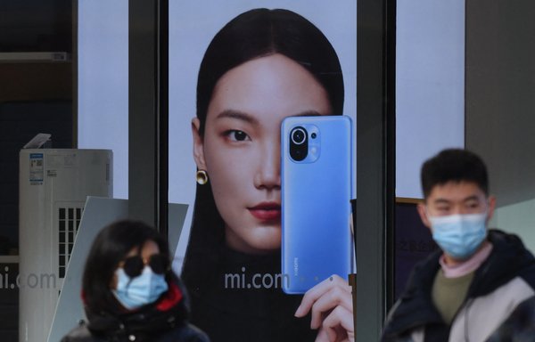 People walk past a Xiaomi store in Beijing on January 15. [Greg Baker/AFP]