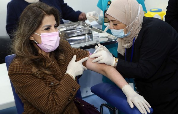A female medic administers a Pfizer-BioTech COVID-19 vaccine injection at a vaccination centre set up in the Kuwait International Fairground in Kuwait City, on December 24, 2020. [Yasser al-Zayyat/AFP]