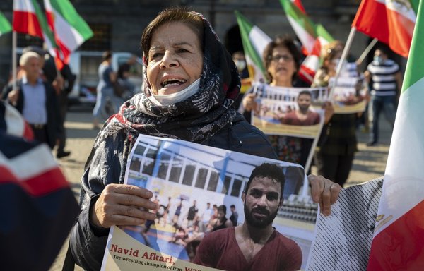 A woman holds a portrait of Iranian wrestler Navid Afkari, during a September 13, 2020, demonstration in Amsterdam against his execution in the southern Iranian city of Shiraz and against the Iranian government. [Evert Elzinga/ANP/AFP]