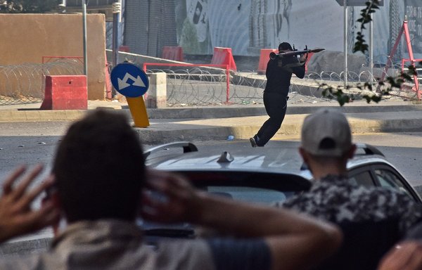 مقاتل موالي لحزب الله وحركة أمل يجري حاملا قاذفة قنابل صاروخية (أر بي جيه) أثناء اشتباكات في الطيونة بضاحية بيروت الجنوبية يوم 14 تشرين الأول/أكتوبر. اندلعت أعمال عنف أثناء مسيرة نظمها حزب الله وحركة أمل في بيروت للمطالبة بإقصاء القاضي الذي يحقق في انفجار المرفأ. [وكالة الصحافة الفرنسية]