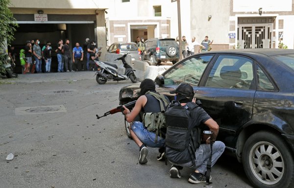 مقاتلون من حزب الله وحركة أمل يحتمون أثناء اشتباكات في الطيونة بضاحية بيروت الجنوبية يوم 14 تشرين الأول/أكتوبر، وذلك أثناء مسيرة للمطالبة بإقصاء المحقق الرئيس في قصية انفجار المرفأ. [أنور عمرو/وكالة الصحافة الفرنسية]