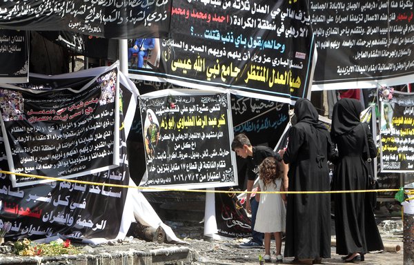 Iraqis gather on July 7, 2016, next to banners of condolences at a memorial for the victims of a suicide bombing that claimed at least 320 lives in Baghdad's al-Karrada district. [Sabah Arar/AFP]