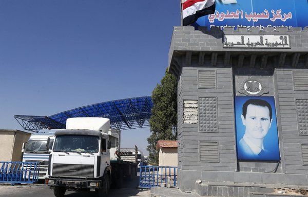 Trucks enter Syria through the Nassib/Jaber border post with Jordan on the day of its reopening, on September 29, after two months of closure due to fighting in southern Syria. [Louai Beshara/AFP]