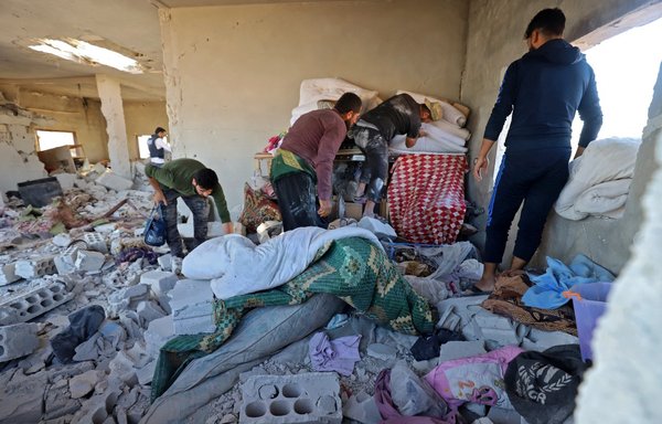 Syrians try to salvage belongings from a house severely damaged by artillery fire in the village of Kansafra in the southern countryside of Idlib province, which reportedly killed four children from the same family, on August 20. [Abdulaziz Ketaz/AFP]
