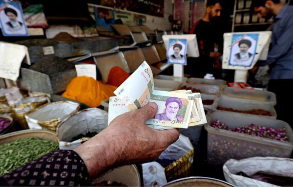 وجه المرشد الأعلى الإيراني على خامنئي يثشاهد في كل مكان في طهران، ويظهر هنا على لافتات في متجر بسوق مولوي جنوب العاصمة يوم 20 حزيران/يونيو. قال كثيرون إن نظام الحكم الذي أسسه روح الله الخميني (المصور على العملة) مدين للحرس الثوري الذي ساعد في إيصاله إلى السلطة. [عطا كيناري/وكالة الصحافة الفرنسية]