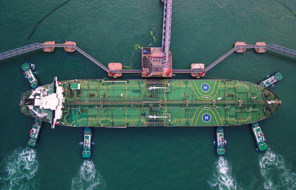 This aerial photo shows tugboats berthing an oil tanker at China's Qingdao port. [STR / AFP]
