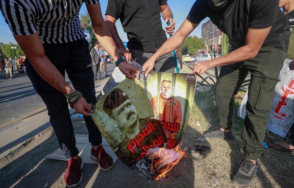 Protesters tied to Iran-backed groups burn portraits of Prime Minister Mustafa Kadhemi and security officials on November 6, a day before a failed attempt on Kadhemi's life. [Ahmad Al-Rubaye/AFP]