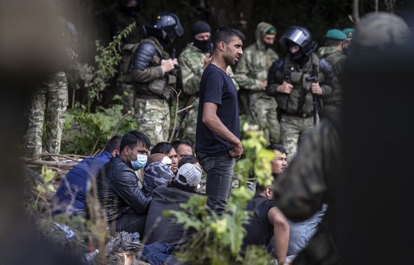 A member of a group of migrants believed to be from Afghanistan tries to confirm their desire to apply for international protection in Poland to Polish volunteer lawyers, in the presence of journalists and Polish parliament deputies, in Usnarz Gorny village near Bialystok, Poland, close to the border with Belarus, on August 20. [Wojtek Radwanski/AFP]