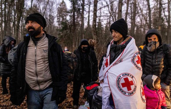 A Kurdish family from Dohuk, Iraq, is assisted by activists from the NGO Grupa Granica (Border Group) as they wait for border guards to take them to Narewka, Poland, near the Polish-Belarusian border on November 9. The family spent about 20 days in the forest and was pushed back to Belarus eight times. They claim they were beaten and frightened with dogs by Belarusian soldiers. [Wojtek Radwanski/AFP]