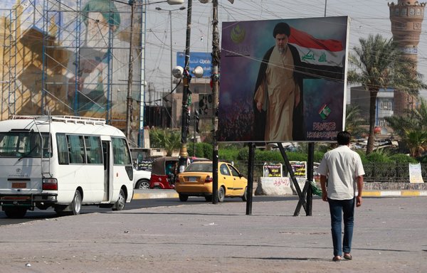 Iraqis pass by a poster of Shia cleric Muqtada al-Sadr in Sadr City in Baghdad on October 17, after the Sadrist movement won 73 of parliament's 329 seats, in the October 10 parliamentary election. [Ahmad al-Rubaye/AFP]