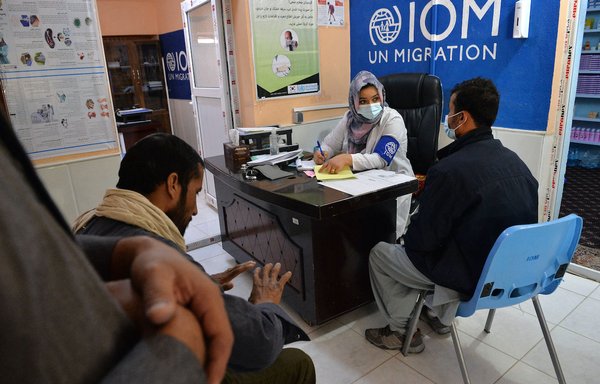 طبيب من منظمة الهجرة الدولية التابعة للأمم المتحدة يفحص المرضى وغيرهم من المرحلين من إيران في مخيم للعائدين في مدينة هرات يوم 19 تشرين الأول/أكتوبر. [هوشانغ الهاشمي/وكالة الصحافة الفرنسية]