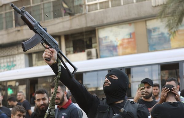A Hizbullah element fires his gun during the October 15 funeral of party members who were killed during clashes in Beirut's southern suburb a day earlier. [Ibrahim Amro/AFP]