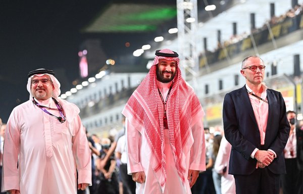 Saudi Crown Prince Mohammed bin Salman Al-Saud (C) and Formula One Group CEO Stefano Domenicali (R) stand on the starting grid prior to the Formula One Saudi Arabian Grand Prix at the Jeddah Corniche Circuit on December 5. [Andrej Isakovic/Pool/AFP]