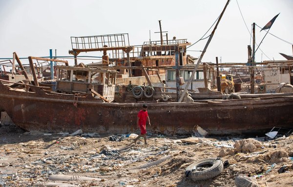 An Iraqi fisherman walks past dilapidated boats docked on the bank of the Shatt al-Arab waterway in the southern Iraqi port city of al-Faw, 90 km south of Basra, on October 26. [Hussein Faleh/AFP]