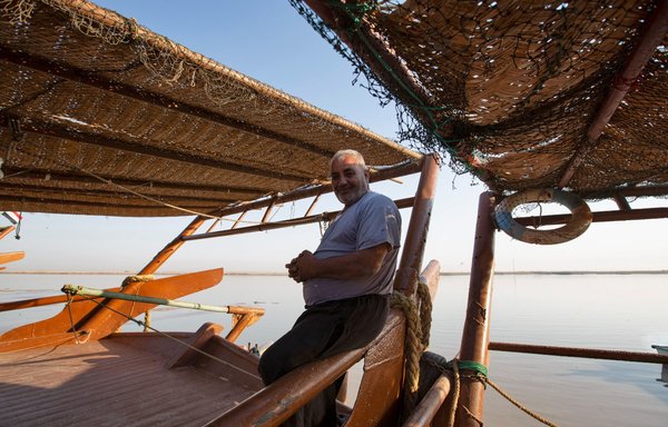 An Iraqi fisherman poses for a picture on his boat anchored on the bank of Shatt al-Arab in the southern Iraqi port city of al-Faw on October 26. [Hussein Faleh/AFP]