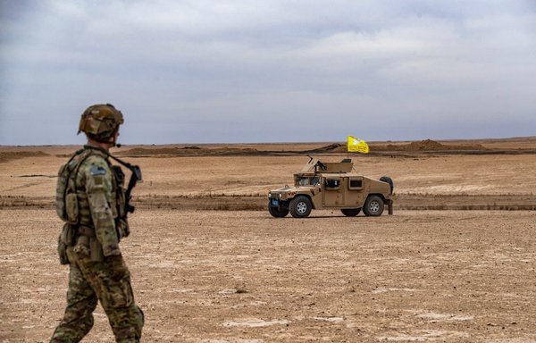 A US soldier walks near a Syrian Democratic Forces military vehicle during a joint exercise between the SDF and the international coalition against ISIS in rural Deir Ezzor on December 7. [Delil Souleiman/AFP]