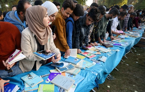 Iraqis browse through books on November 27 during the eighth edition of the annual 'I am an Iraqi, I read' book festival on Baghdad's Abu Nawas street, known for its bookshops and book stalls, along the banks of the Tigris. [Ahmad al-Rubaye/AFP]