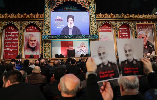 حامیان حزب الله پوسترهای قاسم سلیمانی، فرمانده کشته شده ایرانی، را در حالی که حسن نصرالله رهبر این جنبش در اوایل سال ۱۳۹۹ سخنرانی می کند، در دست دارند. [انور عمرو/ خبرگزاری فرانسه]