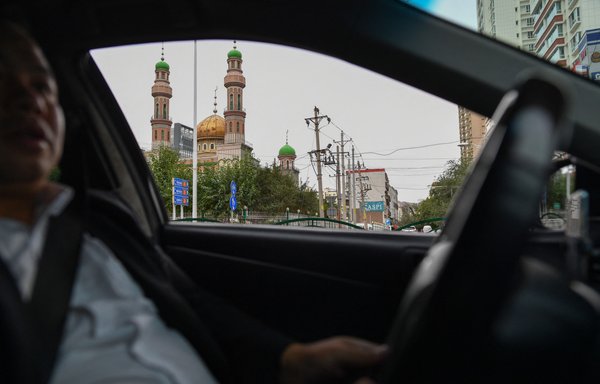 A man drives past a mosque in Urumqi, the regional capital of Xinjiang, on September 11, 2019. Beijing has been destroying mosque minarets and burial grounds where generations of Uighur families have been laid to rest, leaving behind human bones and broken tombs, in what activists call an effort to eradicate the ethnic group's identity in Xinjiang. [Hector Retamal/AFP]