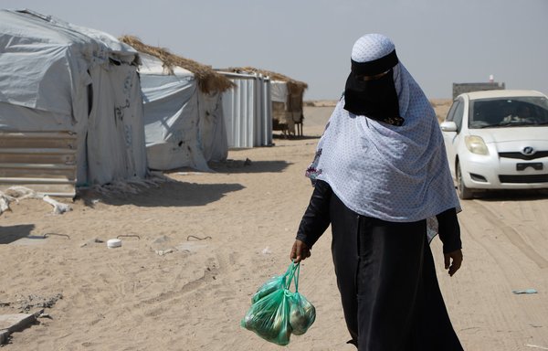 امرأة في مخيم للنازحين تحمل كيسا يحتوي مواد غذائية. وكان وقع ارتفاع معدل التضخم وتكاليف المعيشة في البلاد قاسيا بشكل خاص على العائلات المقيمة في المخيمات. [المجلس النرويجي للاجئين]