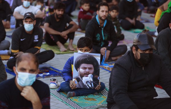 An Iraqi child holds a picture of Shia cleric Muqtada al-Sadr during Friday prayers in Baghdad's Sadr City district on December 3. [Ahmad al-Rubaye/AFP]
