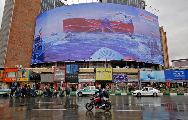 A billboard depicting Iran's Islamic Revolutionary Guard Corps navy units observing a US warship in the Gulf of Oman is seen at Vali-Asr square in Tehran on November 5. [AFP]