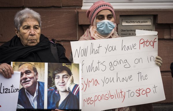 Women demonstrate outside the courthouse where former Syrian intelligence officer Anwar Raslan stands on trial in Koblenz, western Germany, on January 13, after the verdict was spoken on charges for crimes against humanity. [Bernd Lauter/AFP]