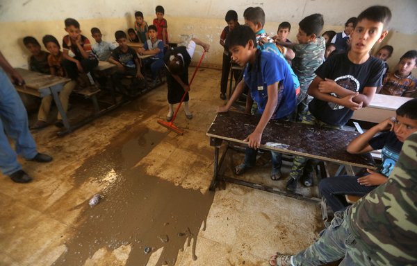 Iraqi students clean their classroom in the village of al-Mazraa near the city of Baiji, on October 19, 2015, after the building was liberated from ISIS. [Ahmad al-Rubaye/AFP]