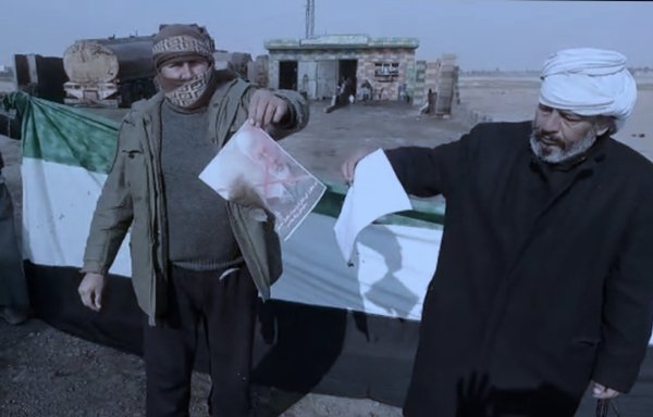 Protesters in the eastern Syria province of Deir Ezzor burn pictures of IRGC commanders during a demonstration. [Eye of the Euphrates]