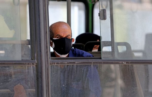 A man, wearing a protective mask because of the coronavirus pandemic, looks out of a bus window in the Iranian capital Tehran on June 22, 2020. [Atta Kenare/AFP]