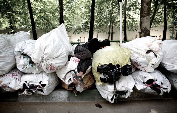 An Iranian scavenger sleeps on a pile of items collected from trash bins as he waits for a vehicle to take them for recycling in northern Tehran on April 12, 2013. [Behrouz Mehri/AFP]