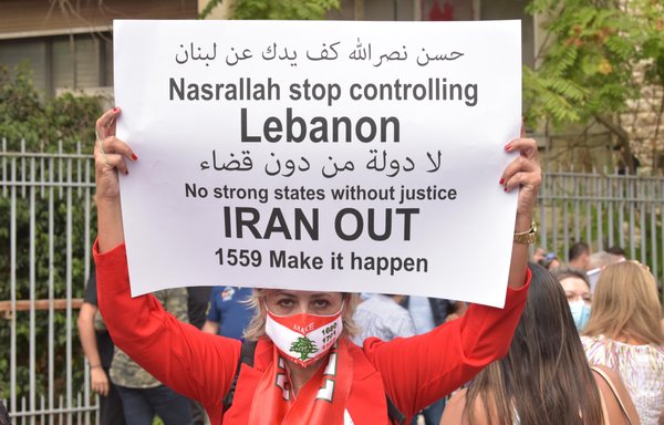 متظاهر يحمل لافتة معارضة لحزب الله وإيران أمام قصر العدل في بيروت بتاريخ 13 تشرين الأول/أكتوبر. [زياد حاتم/المشارق]