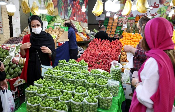 People shop for produce from a merchant's stall at the Tajrish Bazaar in Iran's capital Tehran on April 14, 2021. [Atta Kenare/AFP]