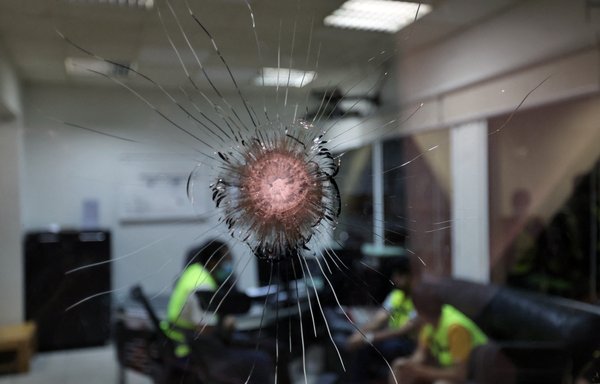 Saudi airport personnel are pictured behind shrapnel-riddled glass at Abha airport on August 31. Twelve people were injured by falling debris after the Saudi military blew up a drone targeting the airport close to the Yemen border, officials said February 10. [Fayez Nureldine/AFP]